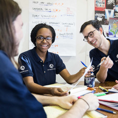 Three people in AmeriCorps uniforms sitting around a table and talking
